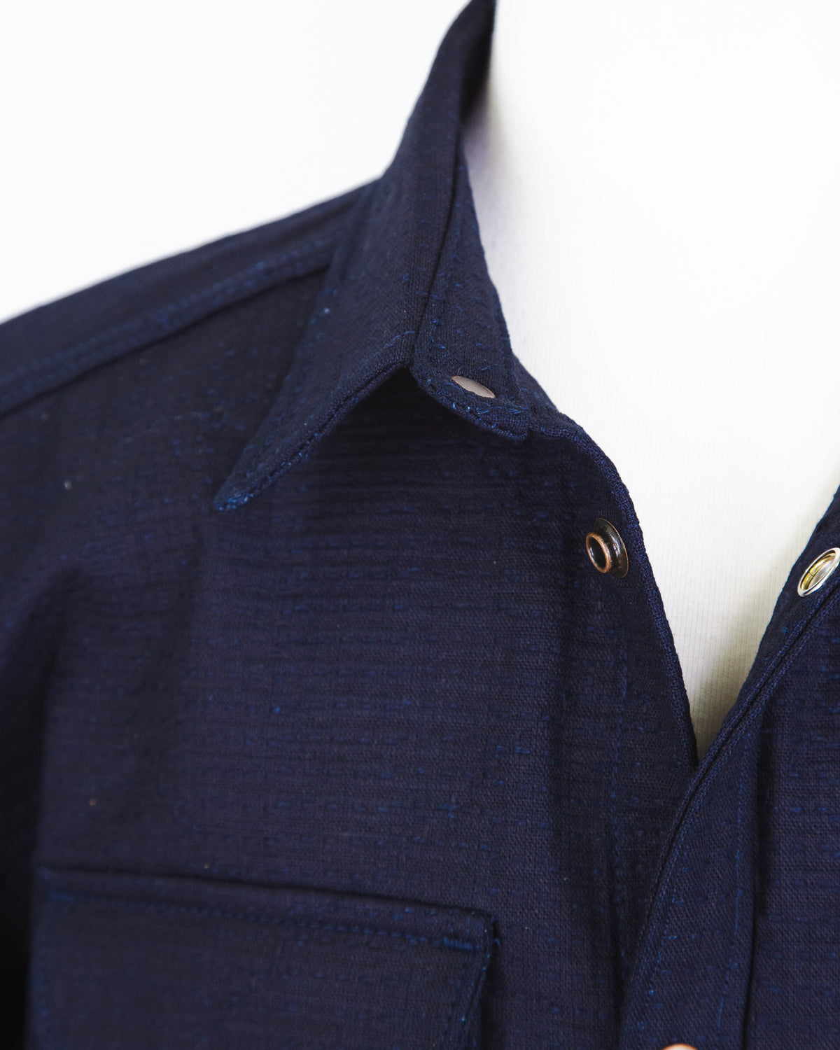 Close-up of a navy blue shirt with a collar and buttons on a white background