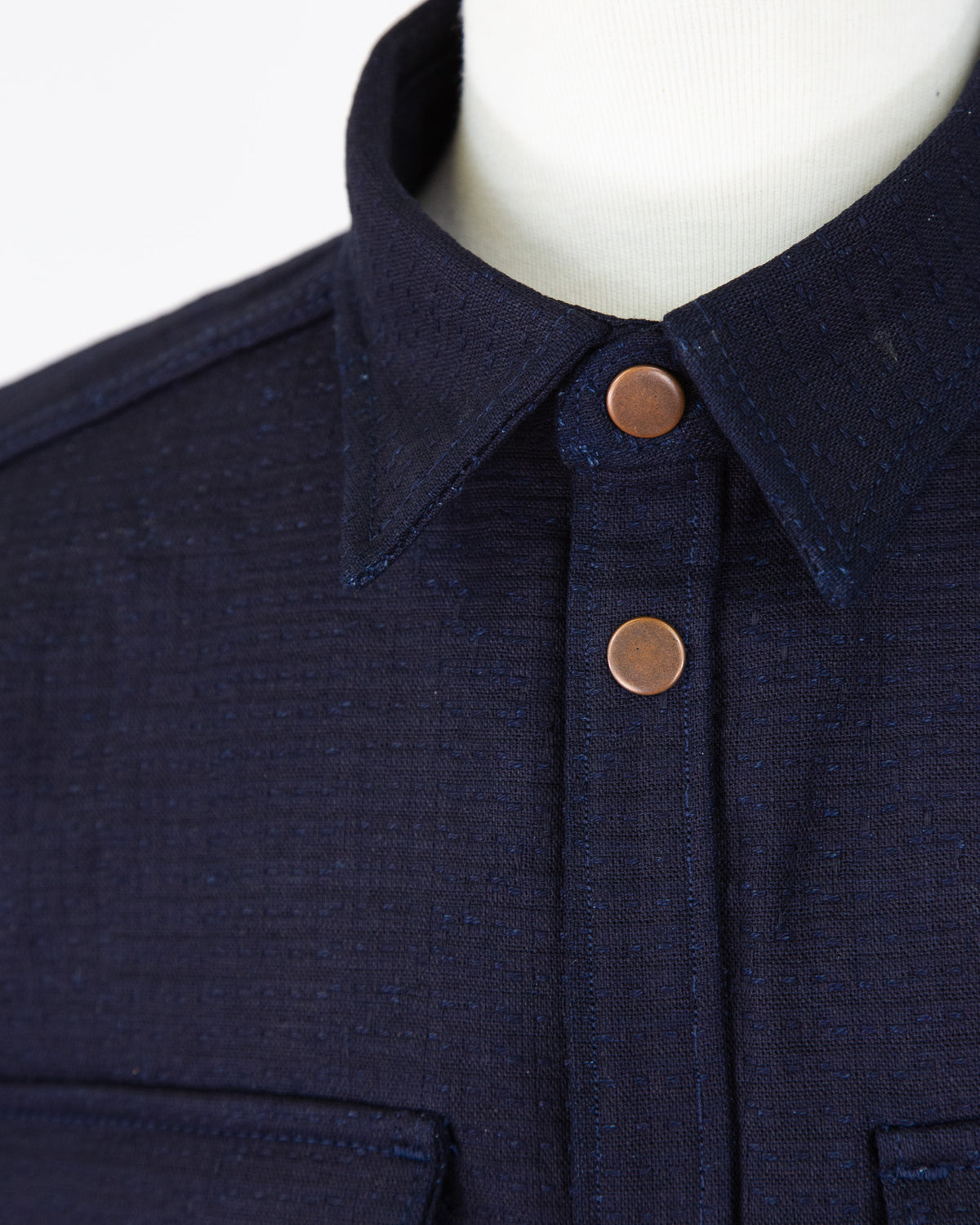 Navy blue jacket with copper buttons on a mannequin against a white background