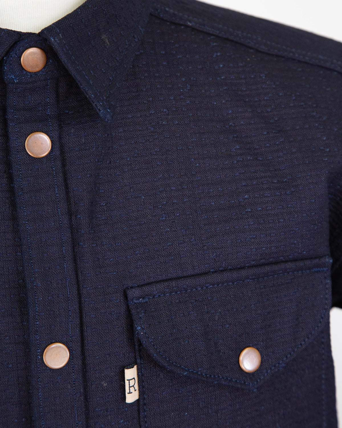 Navy blue denim jacket with button details on a white background