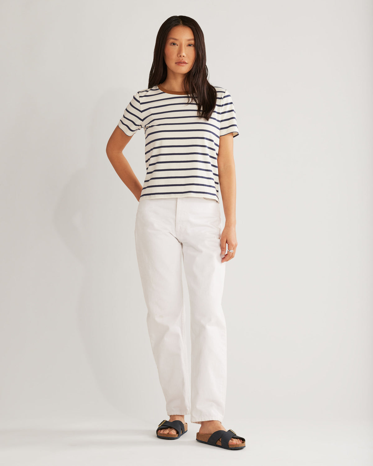Woman wearing a striped shirt and white pants on a plain background