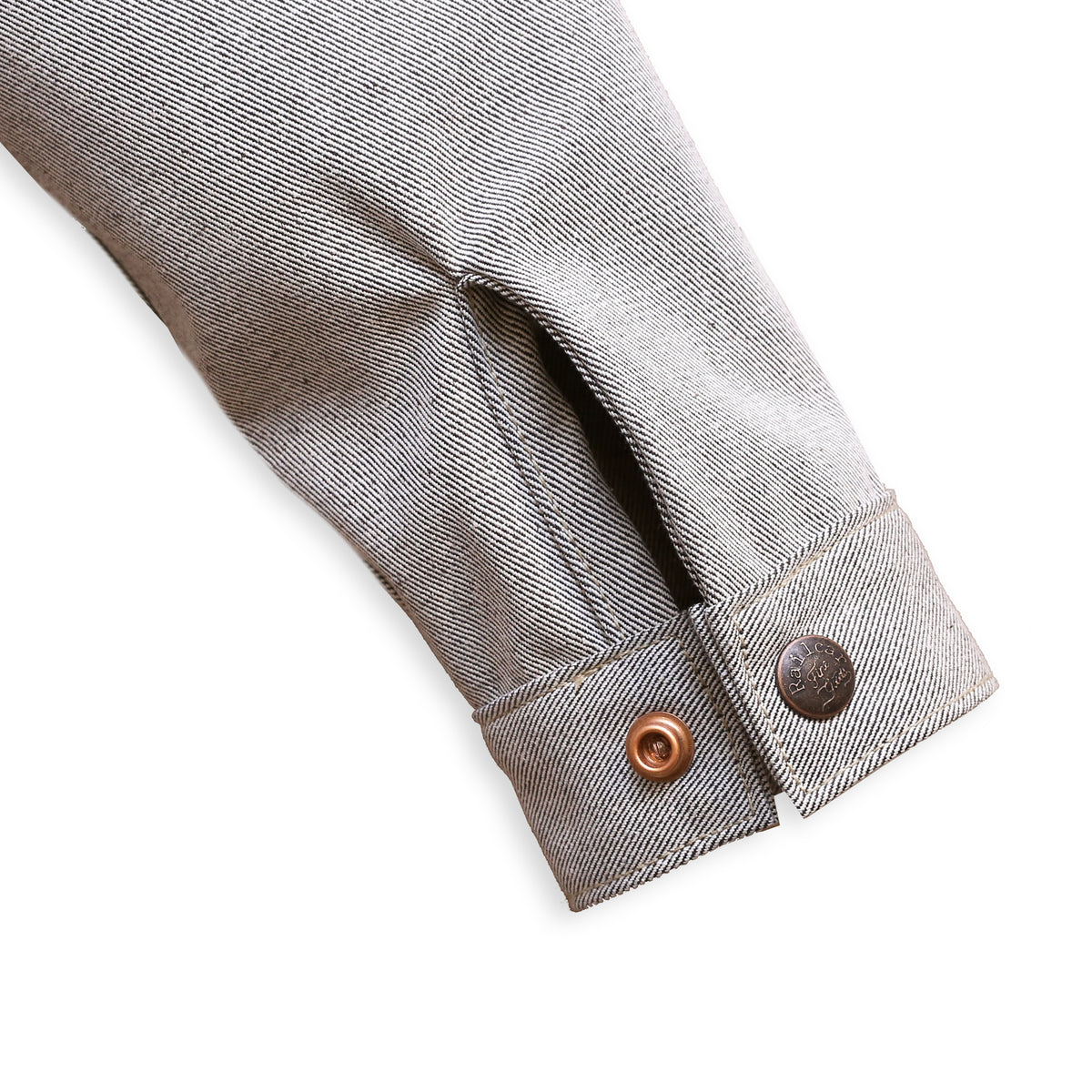 Cuff Detail of a gray Chore Coat with oatmeal denim fabric featuring branded snap buttons.