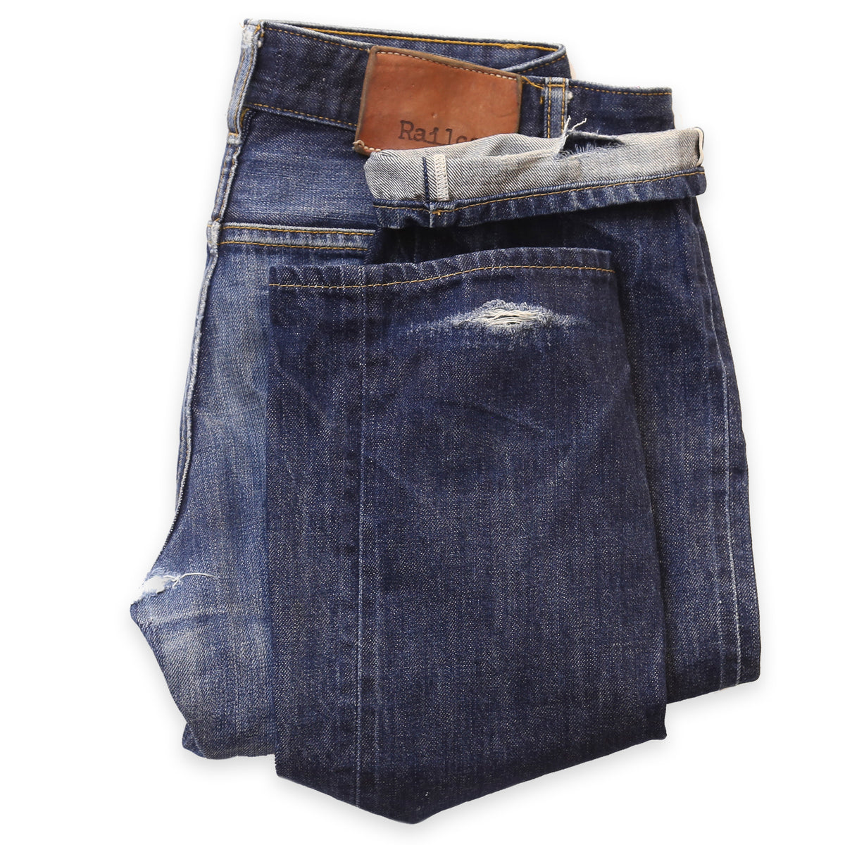 A pair of blue denim jeans with a visible tear at the cuff area, lying flat against a white background.