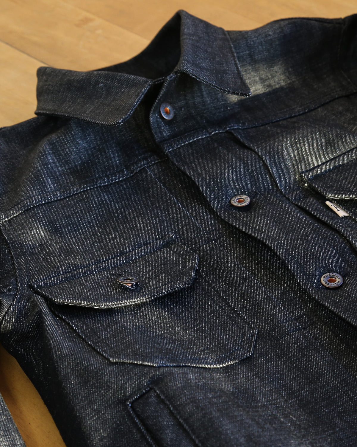 Dark denim jacket with button details on a wooden surface