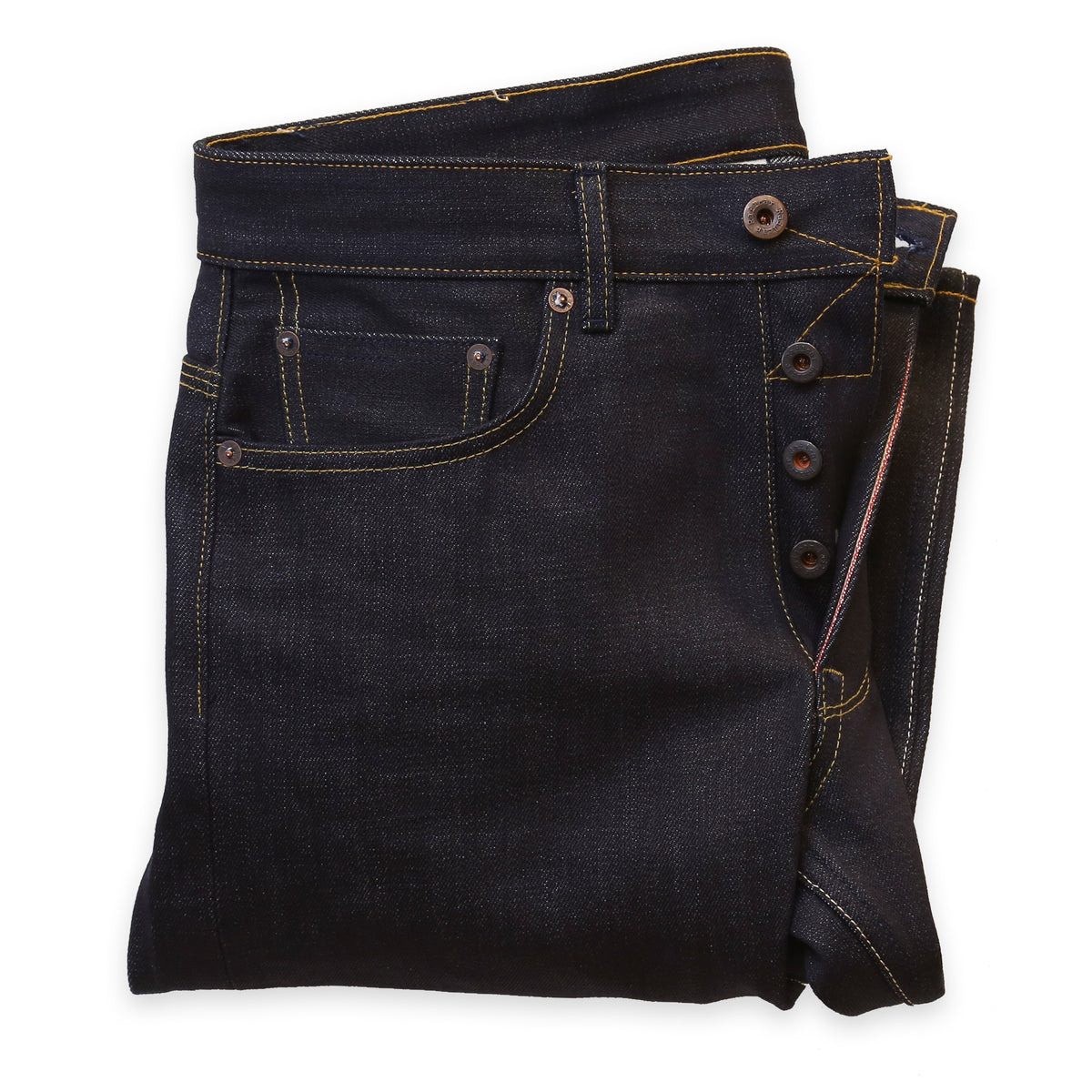 A pair of folded  dark denim jeans showing the button replacement service performed on them.