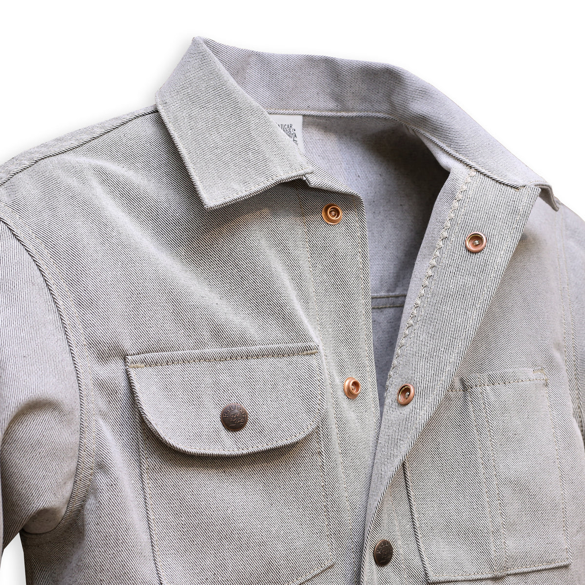 Collar Detail of gray Chore Coat with oatmeal denim fabric, featuring multiple pockets and branded snap buttons.